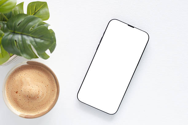 istock Top view a modern smartphone with a blank white screen, coffee cup and plant over white background. Concept online shopping, blog, logo, product, and social media. 2223656513
