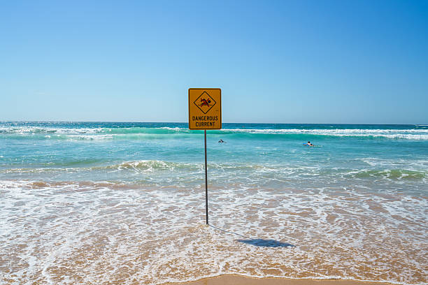 istock Sign warning about dangerous current and no swimming at a beach, waves rolling onto a beach 2223658013