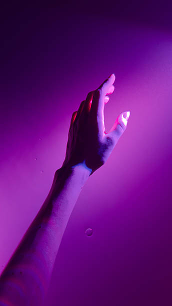 istock A Stunning Visual Representation of an Outstretched Hand Illuminated by Unique Purple Lighting Against a Smooth Textured Background 2223658930
