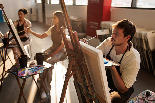 istock Art students concentrating on painting at easels 2223662404