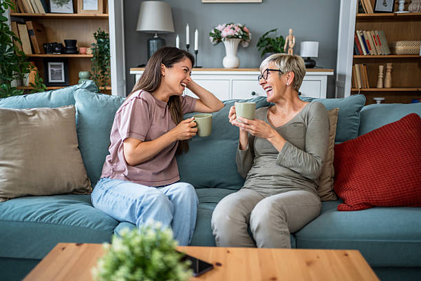 istock Mother and daughter laughing together while drinking tea on sofa 2223665191