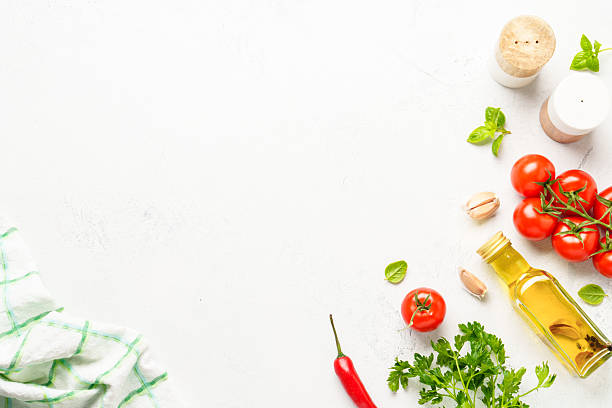 istock Spices, herbs and vegetables with olive oil on a white kitchen table. Flat lay image with copy space. 2223665671