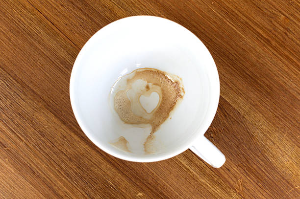 Heart Shape Coffee Stain Inside A White Mug On Wooden Table. Empty cofee cup with a heart on the bottom. Top view, from above, flat lay