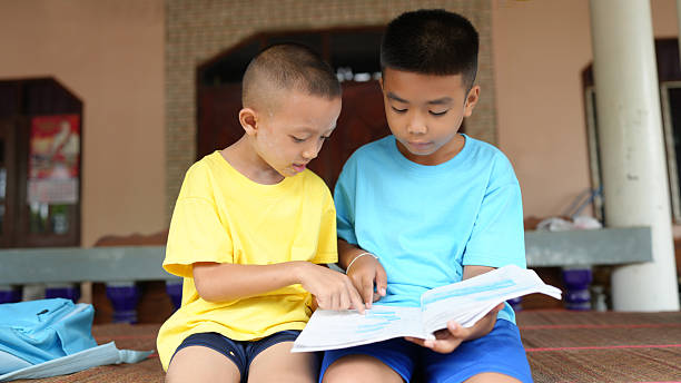 A children studying together, focused on book, sharing knowledge and learning in relaxed environment. their expressions show curiosity and engagement in learning process
