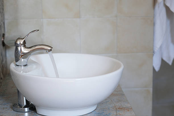 istock Clear water streams from a polished faucet into a sleek white sink 2223681281