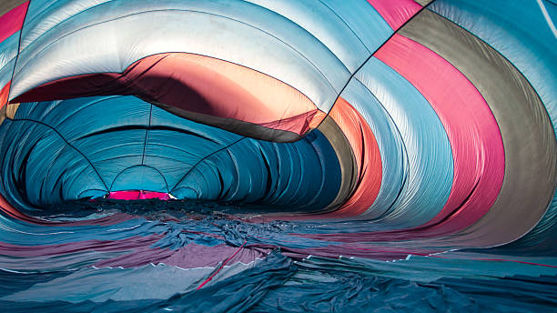 Inside a vibrant hot air balloon before inflation, showcasing colorful fabric patterns and tunnel-like shapes.