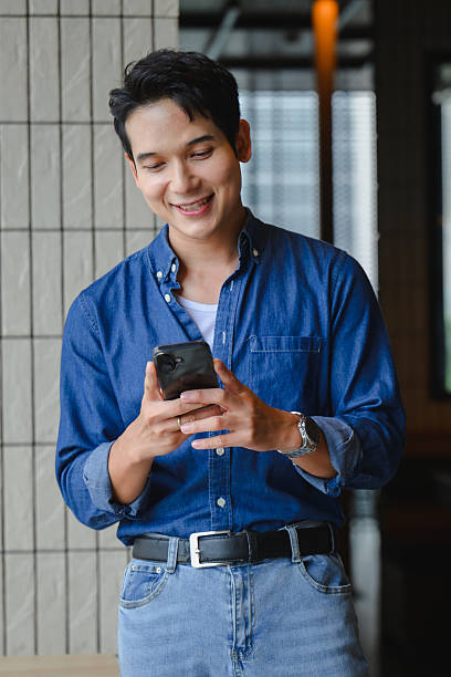 istock Cheerful young Asian professional working on smartphone, networking in contemporary workplace environment, focusing on digital communication 2223688020