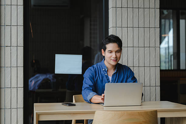 istock Young Asian professional typing intently on laptop, focusing on work within sleek contemporary workspace, embodying digital productivity 2223688035