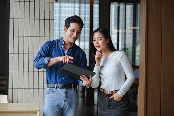istock Two young asian businesspeople looking and discussing over a digital tablet in a modern office 2223688893