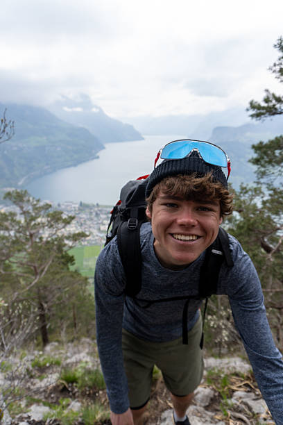 istock Young man scrambles mountain ridge above lake 2223692147
