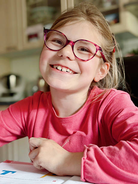 Cute elementary school girl sitting at a desk at home, writing in her workbook and doing school homework. Focused child learning and studying indoors. Concept of education, childhood, home learning.