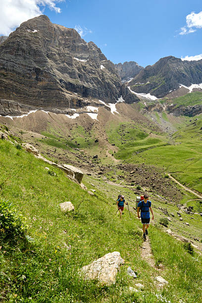 istock Hikers backpacking up a hill with mountains in the background. 2223697508
