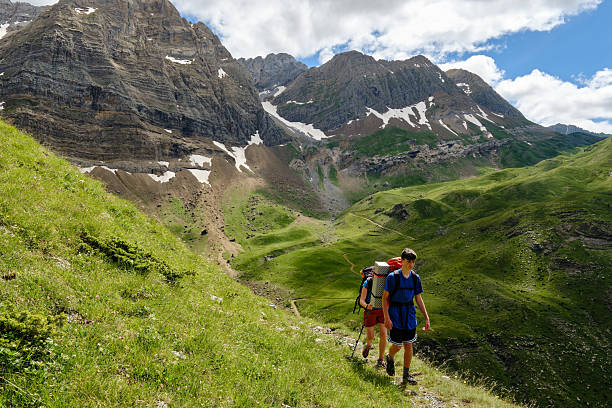 istock Hikers backpacking up a hill with mountains in the background. 2223697536