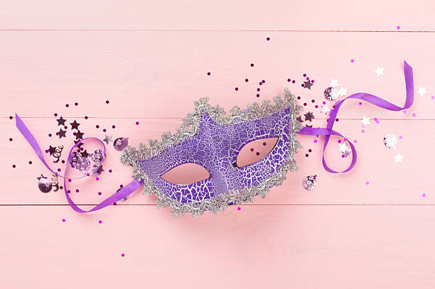 istock Bright carnival mask with confetti on wooden background, top view 2223698196