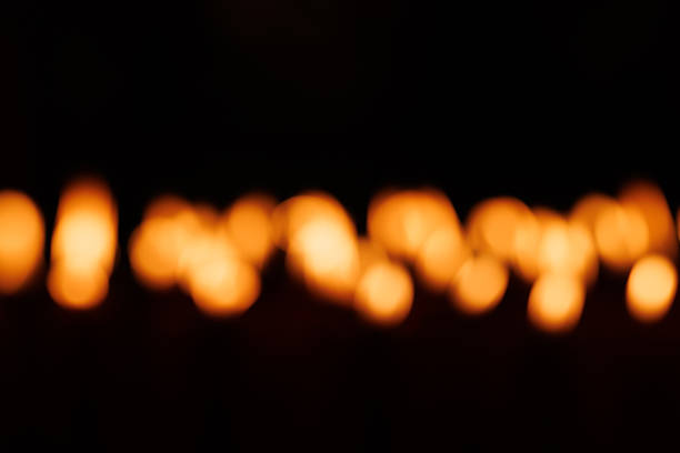 Blurred fire lighting from lit up candle in dark background.