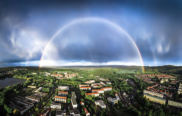 Rainbow during an autumn rain shower over the river IJssel near Zwolle in Overijssel, Netherlands. The reed and trees in the foreground are brightly lit while the sky in the background is dark.