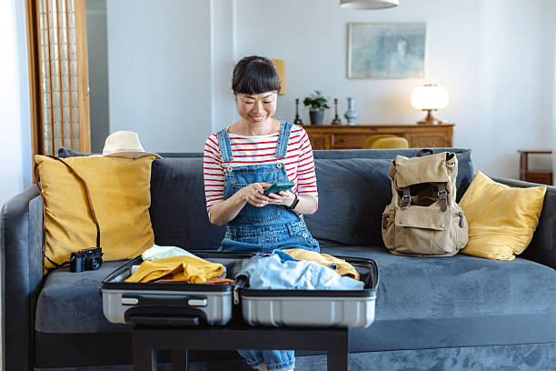 istock Woman preparing suitcase for travel while using her phone 2223707151