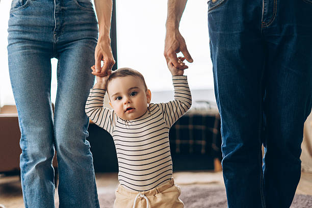 istock Happy baby boy learning to walk holding parents hands 2223713302