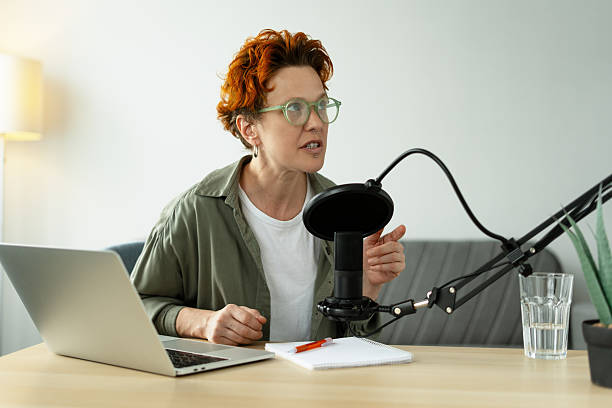 istock Red head, stylish female podcaster recording audio content in her home studio 2223714947