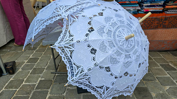 Two open white lace parasols on the pavement
