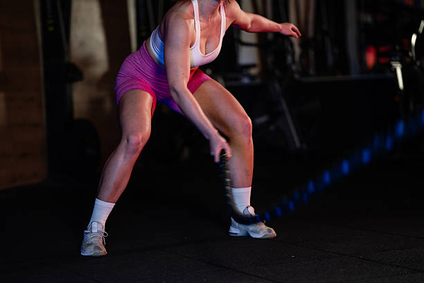 istock Determined sportswoman doing battle ropes exercise in gym for intense workout 2223718944