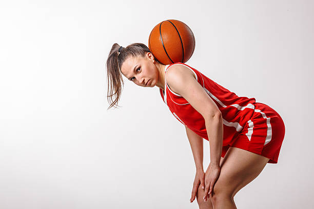 istock Female Basketball Player in Red Uniform Practicing Skills and Showing Determination on White Background 2223720363