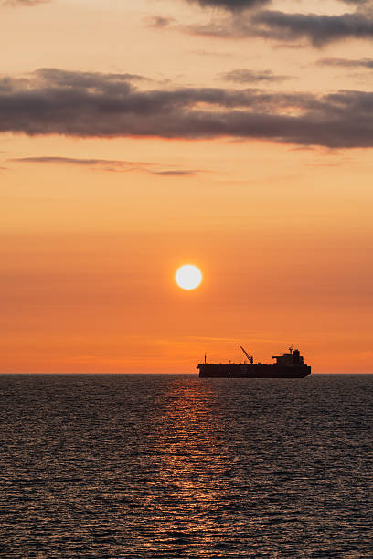 istock A cargo ship silhouette on the horizon during a golden sunset, with a bright solar path reflecting on the sea. 2223725748