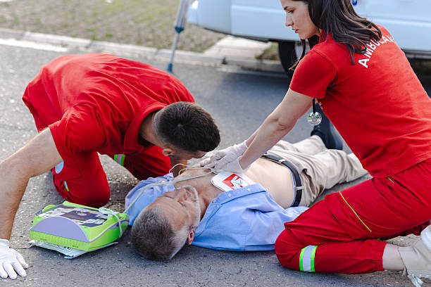 Two paramedics perform CPR on a patient on the ground. Emergency response and life-saving techniques administered.