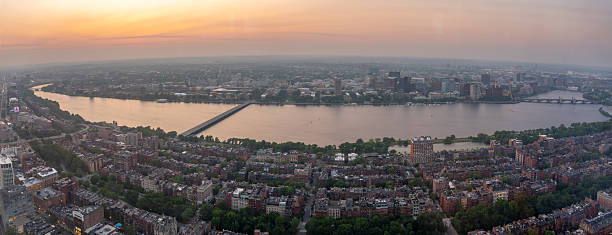 Boston cityscape at sunset with river and bridges.