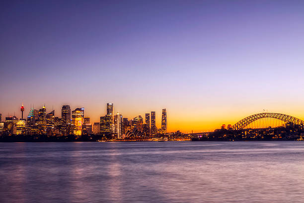 City CBD skyline landmarks on shores of Sydney Harbour at sunset.