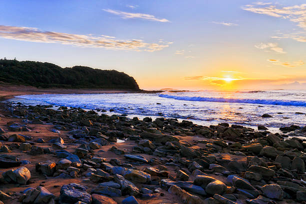Soft gentle rising sun over Pacific ocean horizon off Caves beach coast of Australia - seascape.