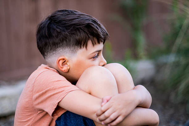 istock Serious concerned sad child boy sitting at the schoolyard looking away 2223730112