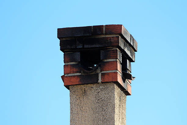 istock Old brick chimney with blackened top against blue sky 2223730403