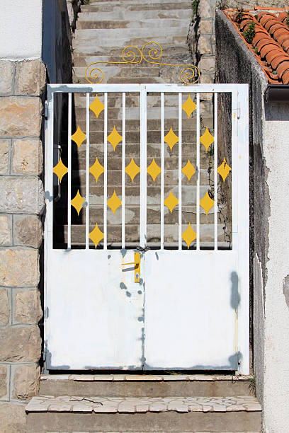 White metal gate with yellow diamond accents blocking stone stairway