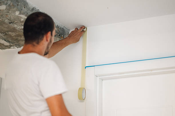 istock Painter applying masking tape on wall before painting 2223733254