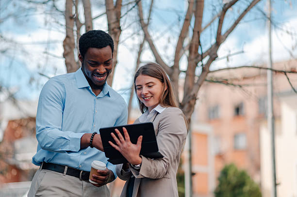istock Smiling business people using digital tablet outdoors 2223733423