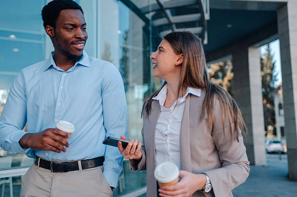 istock Business colleagues enjoying coffee break while walking and talking outside office 2223733443