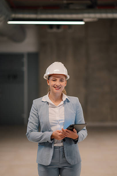 istock Female engineer smiling and holding tablet in building under construction 2223733642