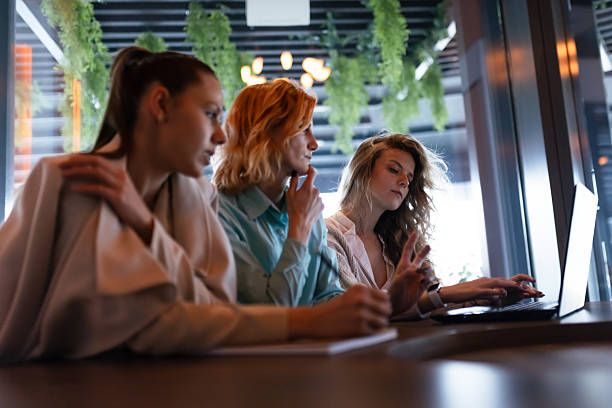 istock Businesswomen collaborating in a modern workspace while discussing ideas and reviewing documents on a laptop at a stylish cafÃ© in the late afternoon 2223737386