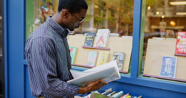 An African American man interacts with a small bookshelf outside of a bookstore in Oregon during the day