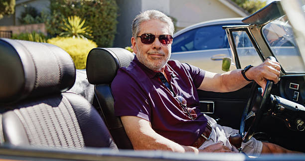 istock Senior Man Smiling into Camera While Sitting in his Vintage Convertible Car 2223740325