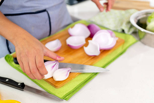 Close-up of a chef slicing fresh red onions on a wooden cutting board, preparing ingredients for a vibrant peruvian ceviche dish