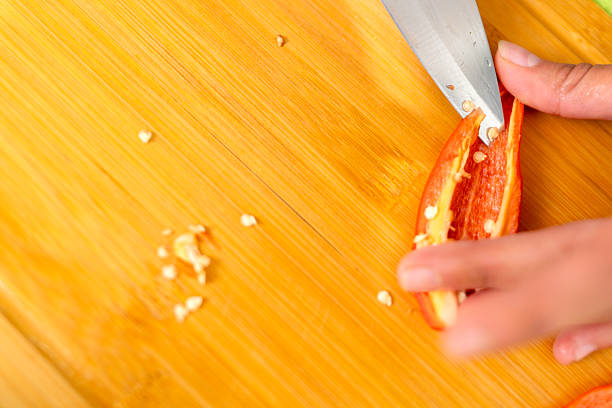 Close-up of chef's hands meticulously deseeding a chili pepper, a crucial step in preparing vibrant and flavorful dishes