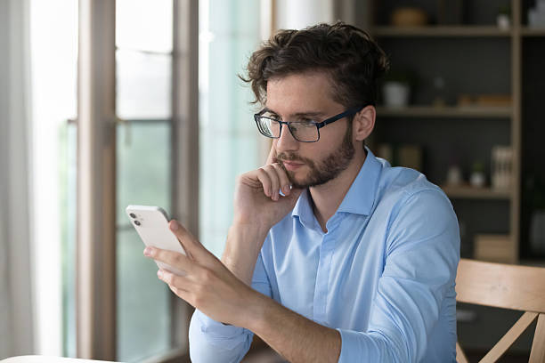 istock Serious man sit at desk read received message on cellphone 2223753435