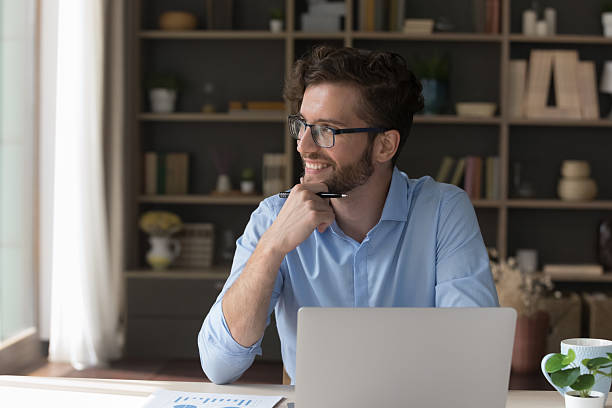 istock Pensive smiling businessman distracted from computer work look into distance 2223753514