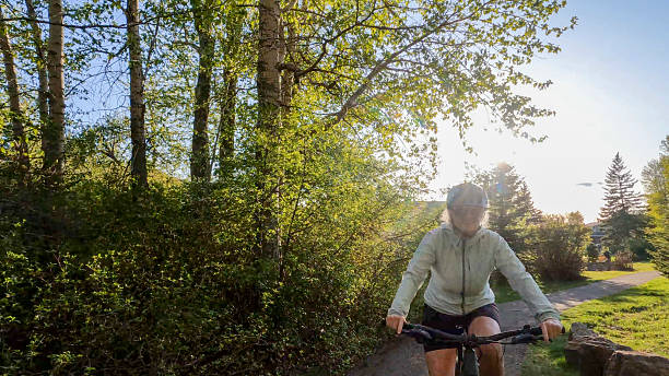 istock Mature woman rides e-bike along pathway in forest 2223757611