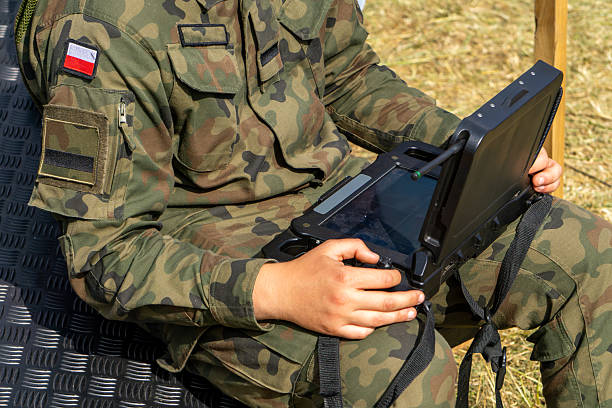 istock Soldier in camouflage uniform operating a military rugged tablet outdoors – modern technology in military operations. 2223759477