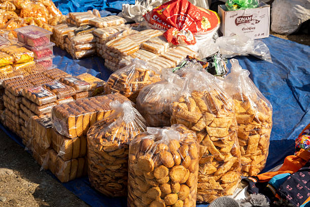 A colorful village mela stall showcases a variety of local biscuits, crunchy rusks, and homemade cakes, reflecting the traditional flavors and charm of rural India.