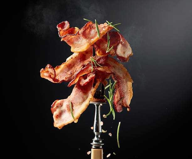 istock Fried bacon on a fork, sprinkled with rosemary and pink salt. 2223761644