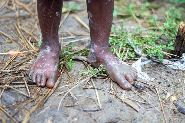 A farmer stands on the muddy ground, leaning on both feet.